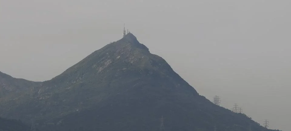 A steep, pointed mountain summit crowned with communication towers and antennas. Stockfoto's