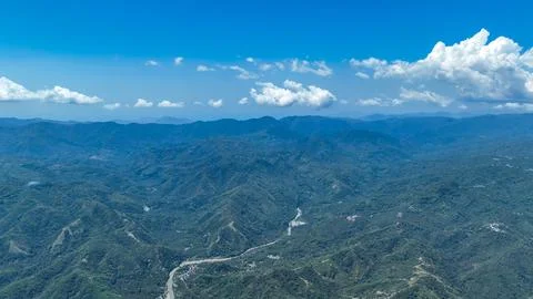 Steep ridges rise over a patchwork of forests and fields, while silver rivers Stock Photos