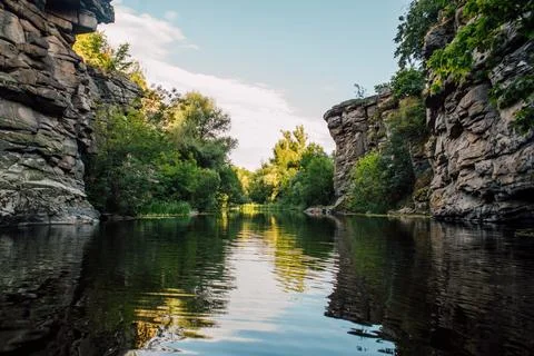Steep Rocky Canyon Cliffs with Trees and Water Reflection Stock Photos