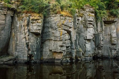 Steep Rocky Canyon Cliffs with Trees and Water Reflection Stock Photos
