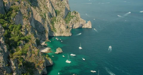 Steep rocky cliffs and turquoise coves filled with boats create a vivid summer Stock Footage 345687543