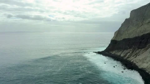 Steep rocky cliffs drop off into coastal waters on overcast day, San Stock Footage 273693746