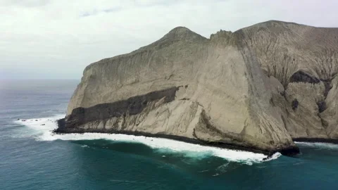 Steep rocky cliffs drop off into coastal waters, aerial pullback, San Stock Footage 276350992