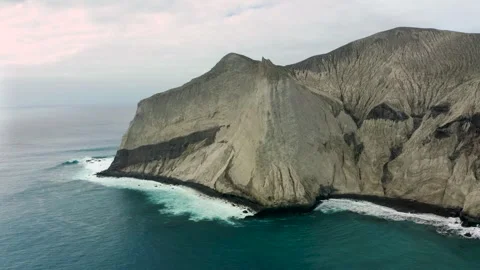 Steep rocky cliffs drop off into coastal waters on overcast day, San Stock Footage 276735509