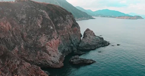Steep Rocky Cliffs Overlooking Calm Ocean and Distant Mountains Stock Footage 326724728
