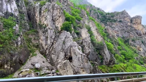 Steep rocky mountain cliffs with green trees and dramatic peaks Stock Footage 310246482