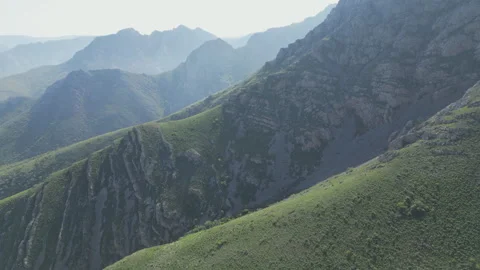 Steep, rugged mountain slopes with patches of green under soft light Stock Footage 334671724