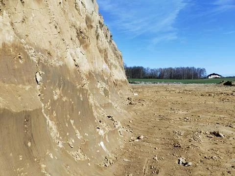 Steep sandy cliff in open field with clear blue sky Stock Photos
