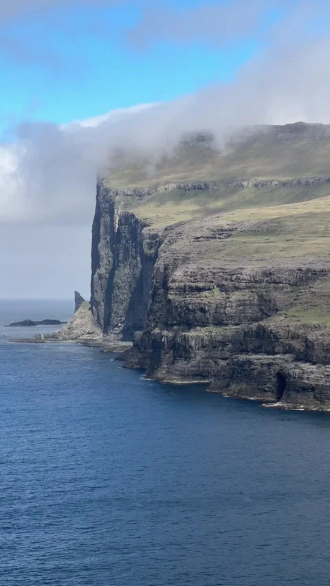 Steep sea cliffs of the Faroe Islands disappear into mist above the Atlantic  Video stock 310947789