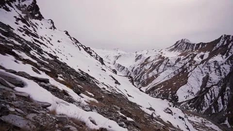 Steep snow filled mountain gully cutting through rocky terrain with rugged Vídeos de archivo 344181986