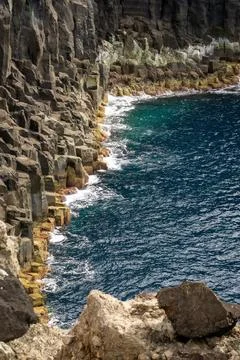 Steep volcanic cliffs meet the deep blue Atlantic Ocean in Terceira, Azores, Stock Photos