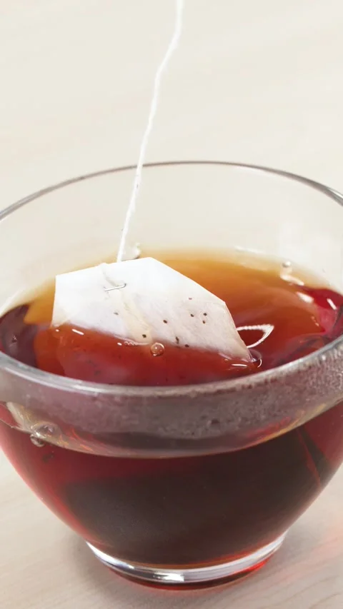 Steeping and Dipping Tea Bag in Clear Glass Cup of Hot Black Tea Stock Footage 345710338
