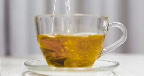 Steeping fragrant tea, loose bag dangling from transparent mug, resting on Stock Footage 306633496