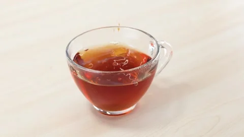 Steeping Tea Bag in Glass Cup on Wooden Table Stock Footage 345784075