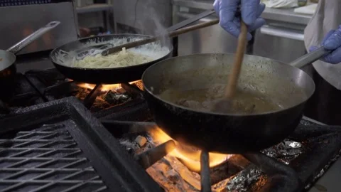Steering beef stew in a pan on a fire stove. Professional cooking in restaurant  Stockbeeldmateriaal 72653286