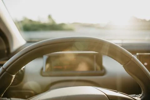 Steering wheel and view through glass on sunset background. Stock Photos