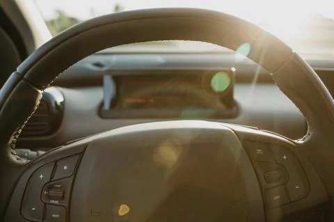 Steering wheel and view through glass on sunset background. Stock Photos