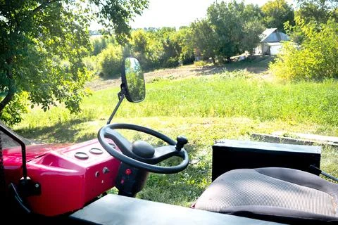 Steering wheel close up of small red modern new tractor standing on a farm,.. Stock Photos