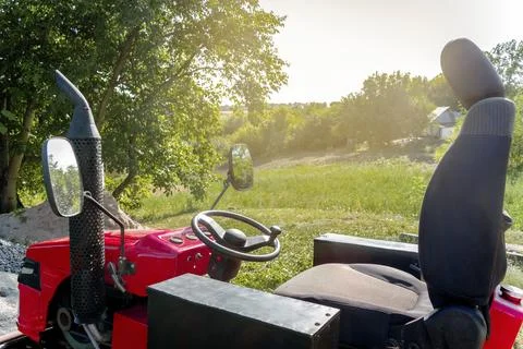 Steering wheel close up of small red modern new tractor standing on a farm, f Stock Photos