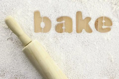 Stencil word "bake" made with flour on wooden table Stock Photos