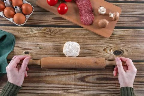 Step 5: The womans hands prepare to roll out the dough on a wooden table. Foto stock