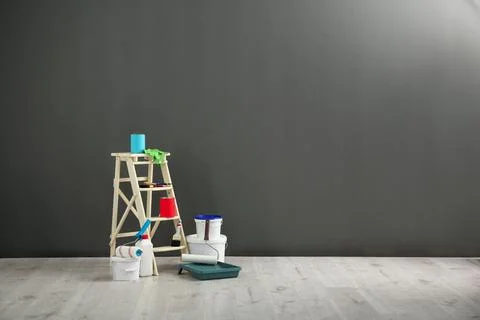 Step ladder and decorator's tools near grey wall Stock Photos