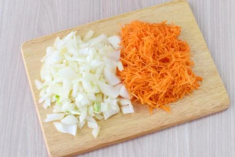 Step by step cooking. Cut onion and carrots on a wooden cutting board Stock Photos