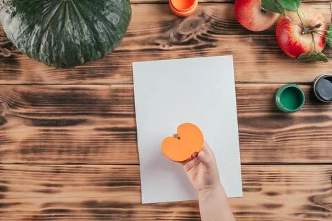 Step-by-step Halloween tutorial pumpkin apple prints. Step 7: Child hand hold Stock Photos
