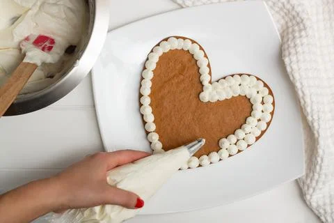Step-by-step heart-shaped cake recipe instructions. Step 10: Apply the cream  Stock Photos
