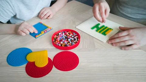 Step-by-step instruction for thermo mosaic: step 3.Two children create pattern Stock Photos