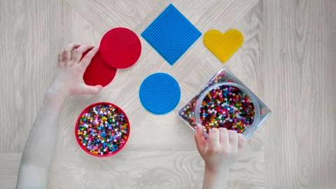 Step-by-step instruction for thermo mosaics: step 2.Kid's hands,forms,beads Stock Photos