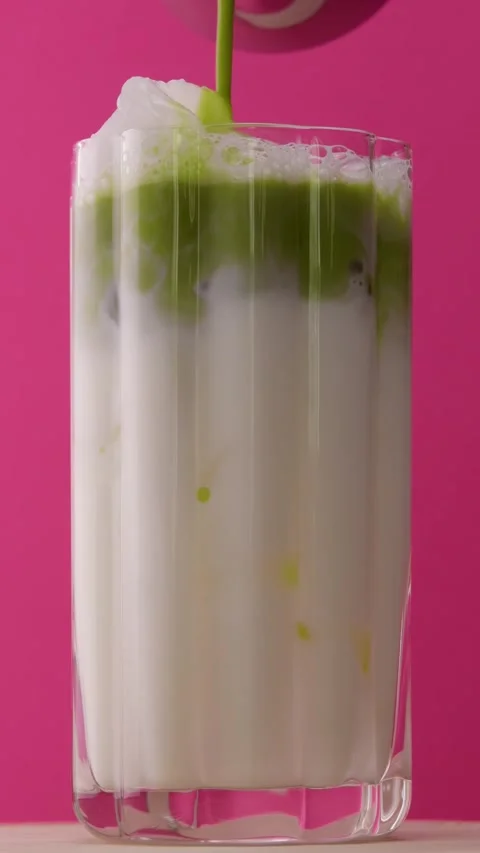 Step-by-step matcha latte preparation with milk and ice in clear glass, vibrant Stock Footage 318004411