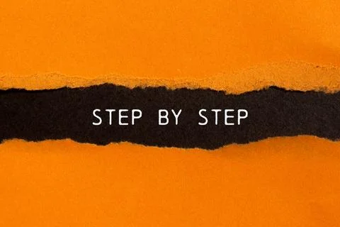 Step by step message written on ripped torn orange paper on black background. Foto stock