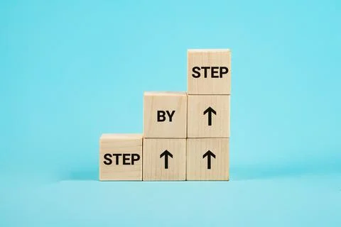 Step by step text. The word step by step on wooden cubes. Achievement or Stock Photos