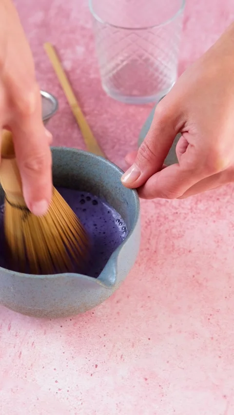 Step by step tutorial making blue matcha tea. Step three , whisking until froth Video stock 294317913