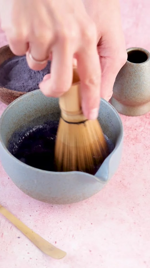 Step by step tutorial making blue matcha tea. Step two , adding water and whisk Video stock 294320553