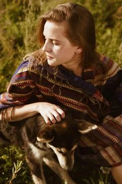 On the steppe grass sits a girl dressed in the style of hippies or boh and Stock Photos
