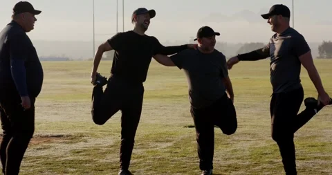 Stepping onto dewy field, senior men linking arms, stretching quadriceps warming Stock Footage 339650834