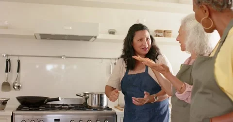 Stepping forward after friends pointing, woman in blue apron adjusting pot on Stock Footage 342233945