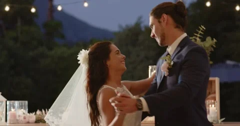 Stepping onto terrace under string lights, bride and groom dancing first dance Stockbeeldmateriaal 316688523