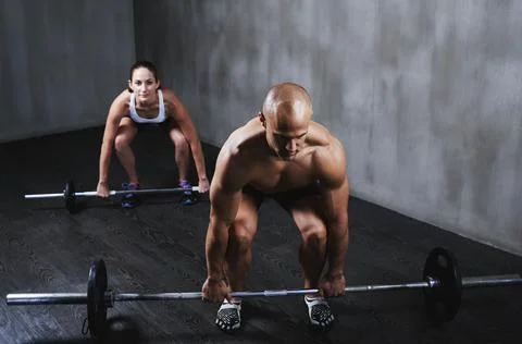 Stepping up their fitness routine. two people lifting barbells during a gym Stock Photos