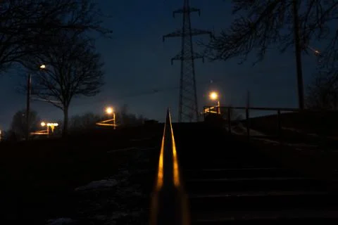 The steps are up, the railing is illuminated by an orange street lamp. Evenin Stock Photos