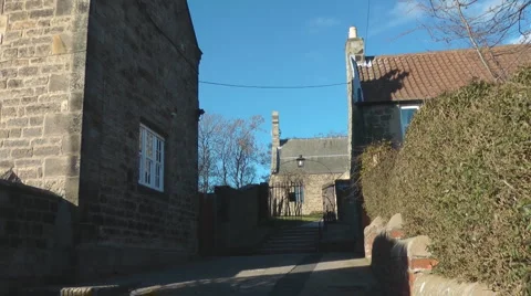 Steps between stone cottages to ancient village church in Norman style, Stock Footage 1097473