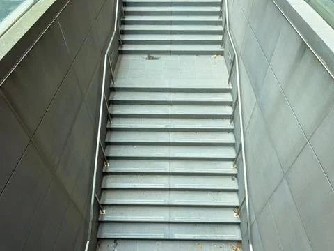Steps lead down from a modern building to a lower level in a city setting d.. Fotos de archivo