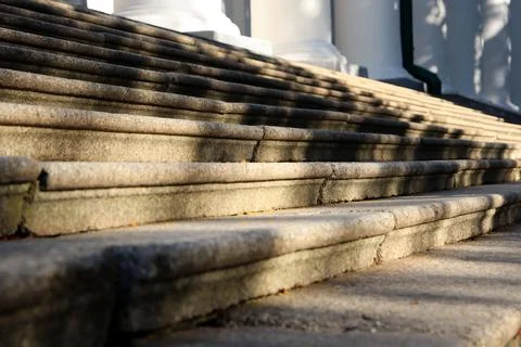Steps lead to a large building under bright sunlight at midday with clear Stock Photos