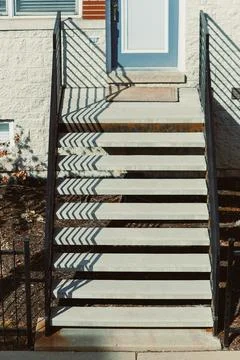 Steps leading to a blue door at a house with shadows on the stairs during t.. Stock Photos