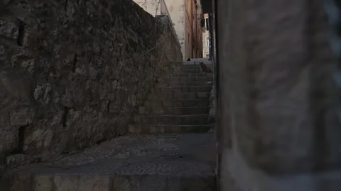 Steps leading up through a historic stone pathway in Dubrovnik old city with Stock Footage 296013445