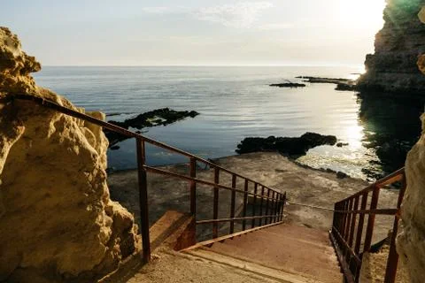 Steps to the sea stone beach. The setting sun is reflected in the water Stock-Fotos