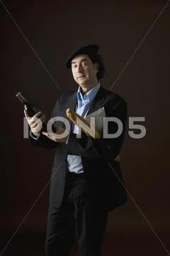 Stereotypical french man holding a bottle of wine, baguette and a newspaper Stock Photos