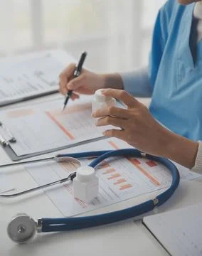 Stethoscope and background doctor using laptop at desk in clinic working on.. Stock Photos